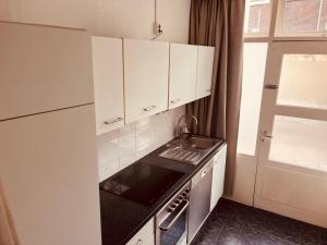 a small kitchen with white cabinets and a sink at naMaaStay in Maastricht +37 photos