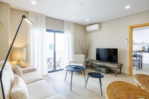 a living room with a white couch and a tv at Casa Ilda in Olhão