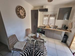 a kitchen with a glass table and chairs and a clock at Maison cocon Bali in Saint-Pierre-des-Corps