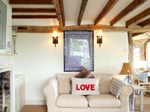a living room with a white couch with a love pillow on it at Prospect Cottage in Wittersham