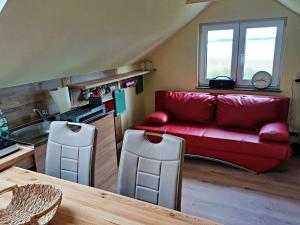 a living room with a red couch and a table at Ferienwohnung OG Seglerblick am Achterwasser in Ziemitz