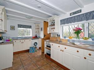 a large kitchen with white cabinets and a window at Bridge View - Cottage in Middle Mill