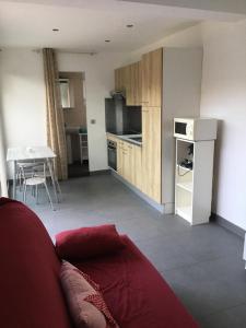 a living room with a red couch and a kitchen at Studio meublé au calme avec terrasse et climatiseur mobile in Fréjus