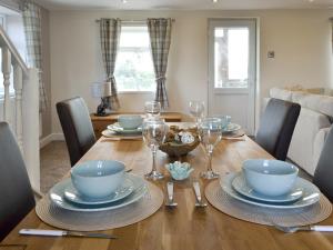 a dining room table with plates and wine glasses at Granary Cottage in Bempton