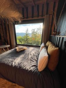 a bedroom with a bed with a large window at La Muzetiere Cabane du crêt in Chamelet