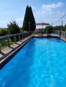 ein blauer Swimmingpool mit einem Tisch und einem Sonnenschirm in der Unterkunft Casa Bartulo in Castrofeito