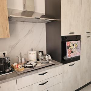 une cuisine avec des armoires blanches et un four à plaques de cuisson dans l'établissement Appartamenti Ohana, à Reggio de Calabre