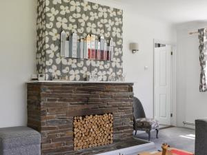 Una sala de estar con una chimenea de ladrillo con un estante encima. en Trelawney Bungalow, en Callington