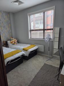 a bedroom with two beds and a window and a fan at Luxury City Center Apartment in Liverpool
