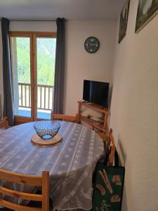 une salle à manger avec une table et une télévision dans l'établissement Bel appartement à la Montagne, à Cervières