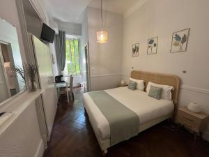 a bedroom with a bed and a table and a tv at Nice Garden Hotel in Nice