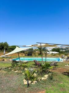 a pool with a tan umbrella and some chairs at casa entre mer et montagne in Arcos de la Frontera