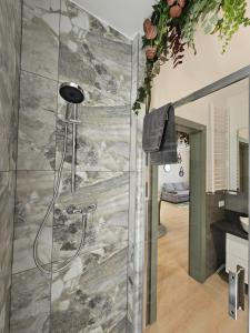 a shower in a bathroom with a stone wall at Oliwkowy - stylowy Apartament w naturalnym klimacie in Częstochowa