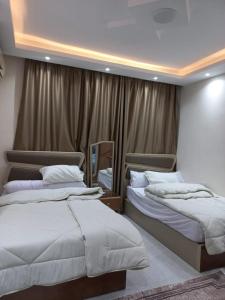 two beds in a hotel room with curtains at استديو شارع منتصر امام مستشفي الجهاز الهضمي المنصوره والجامعه in Mansoura