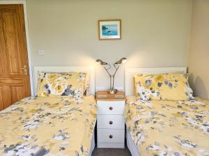 a bedroom with two beds and a lamp on a night stand at Five Oaks B&B - New Quay in Llanina