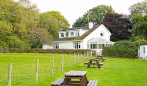 a white house with picnic tables in the yard at Five Oaks B&B - New Quay in Llanina