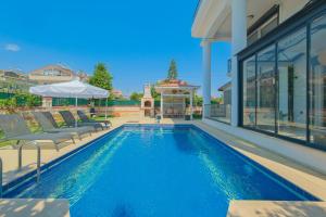 ein Swimmingpool mit Stühlen und ein Haus in der Unterkunft VillaSerenity5 in Fethiye