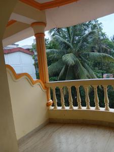 a balcony with a view of a palm tree at Bright Beach Homestays in Calangute +8 photos