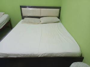 a bed with white sheets and pillows in a room at Karen Tibura Homestay in Siburan
