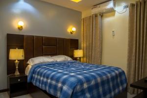 a bedroom with a bed with a blue plaid blanket at Lakeluxhomes Apartment in Ibadan
