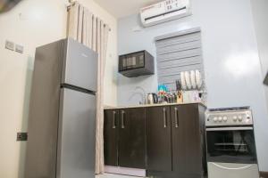 a kitchen with black cabinets and a refrigerator at Lakeluxhomes Apartment in Ibadan