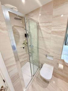 a bathroom with a toilet and a glass shower at The Lookout-Sea Views-Balcony-Free parking in Ramsgate +26 photos