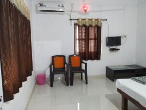 a living room with two chairs and a tv at Savali Cottage in Nagaon
