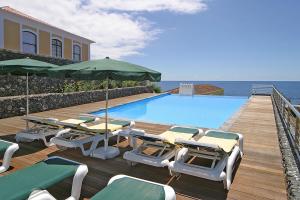 a pool with chairs and umbrellas on a wooden deck at Quinta das Merces in Angra do Heroísmo