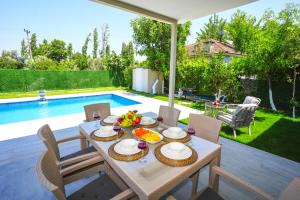 a table with food on it in a backyard with a pool at Villa Albatross in Ortaca