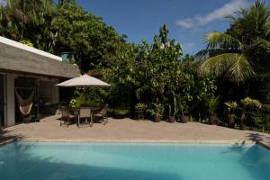a swimming pool with a table and an umbrella at Casa no Lago in Ananindeua