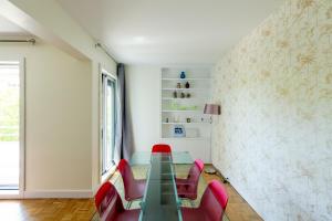 Un comedor con una mesa de cristal y sillas rojas. en Modern Apartment - Pont Mirabeau, en París 37 fotos más