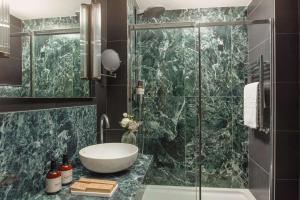 a bathroom with a sink and a glass shower at NH Collection Milano President in Milan +104 photos