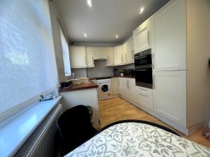 a small kitchen with white cabinets and a sink at 2 Bedroom-House-Sleeps 5 In Front Horley Station -Near Gatwick Airport in Horley