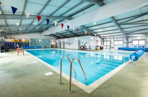 a large indoor swimming pool with blue water at Well equipped beach caravan in Leysdown-on-Sea
