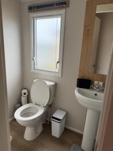a bathroom with a toilet and a sink and a window at Well equipped beach caravan in Leysdown-on-Sea +7 photos