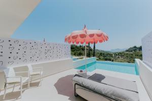 a patio with a table and chairs and an umbrella at The Palms Concept Hotel Adults Only 16 Plus in Faliraki