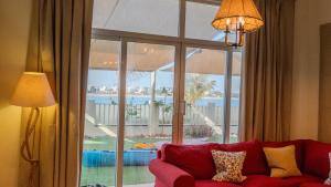 ein Wohnzimmer mit einem roten Sofa und einem großen Fenster in der Unterkunft Beach Front Bermuda Villa Mina AlArab Ras Al Khaimah in Ras al Khaimah