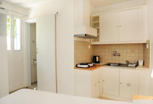 a kitchen with white cabinets and a sink at Nikoleta Rooms in Tinos