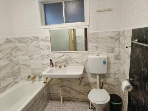 ein Badezimmer mit Waschbecken, Toilette und Badewanne in der Unterkunft Queen Room in Carlingford near Shops and Station - NC4 in Stanwell Park
