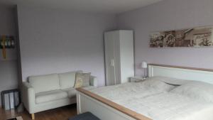 a bedroom with a white bed and a chair at Travemünde Kleine Perle in Lübeck