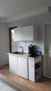a kitchen with white cabinets and a sink at Travemünde Kleine Perle in Lübeck