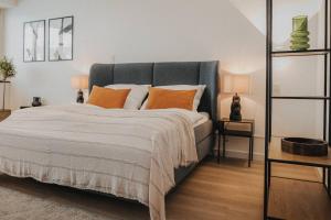 ein Schlafzimmer mit einem großen Bett mit orangefarbenen Kissen in der Unterkunft DOWNTOWN Apartment mit Luxusbad am Hafen nur 5 Minuten zu Fuß in die Innenstadt und zum Bahnhof! in Oldenburg
