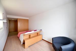 a bedroom with a bed and a desk and a chair at Casa da Baía - Guest House in Horta