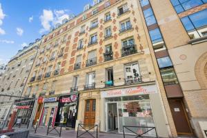een groot gebouw in een stadsstraat met een winkel bij Beautiful renovated studio metro in Levallois-Perret