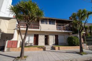 a building with two palm trees in front of it at Falkner & La costa in Mar del Plata