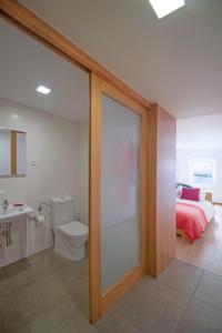 a bathroom with a toilet and a bed in a room at Casa da Baía - Guest House in Horta