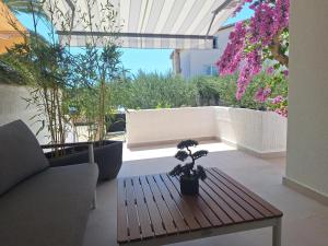 a patio with a bench and a table and flowers at FA-NI in Novalja