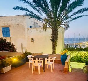 a patio with a table and chairs and a palm tree at Casa Sea view Blu Marettimo in Marettimo