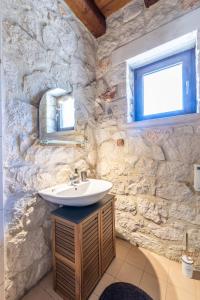 a bathroom with a sink and a stone wall at Platanus Inn Villa by "elite" in Vanáton