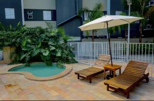 two chairs and an umbrella next to a small pool at Almaré Home in Ubatuba